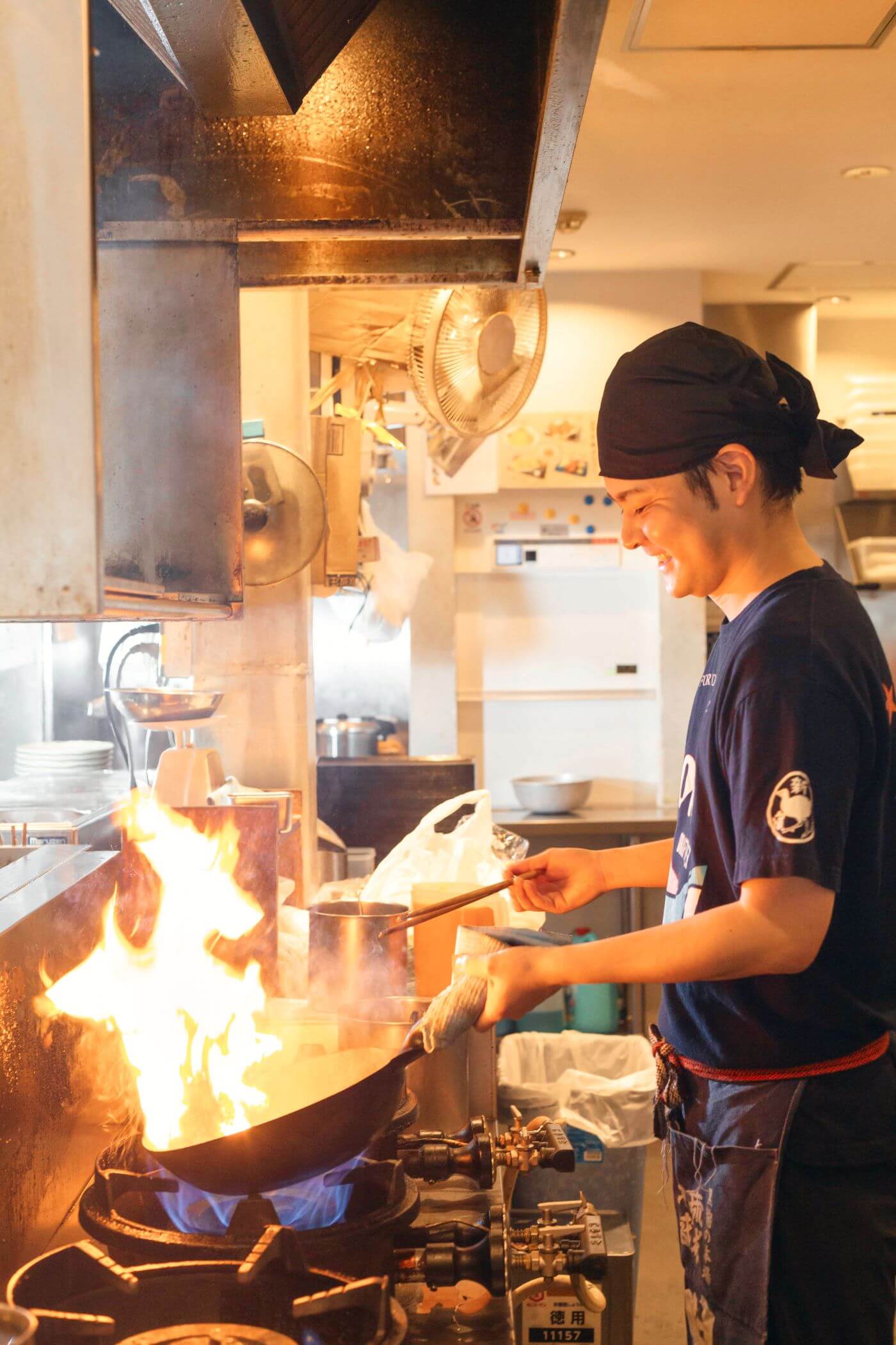 店の厨房で調理をする新里